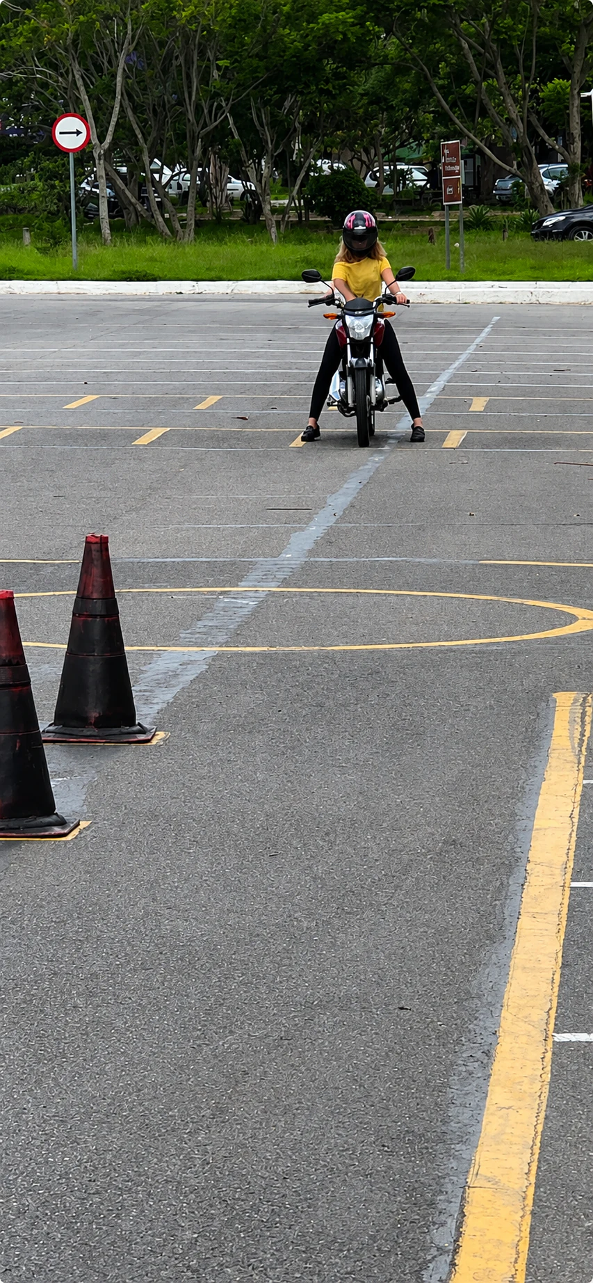 Aluna posicionada em uma motocicleta no circuito de treinamento entre cones